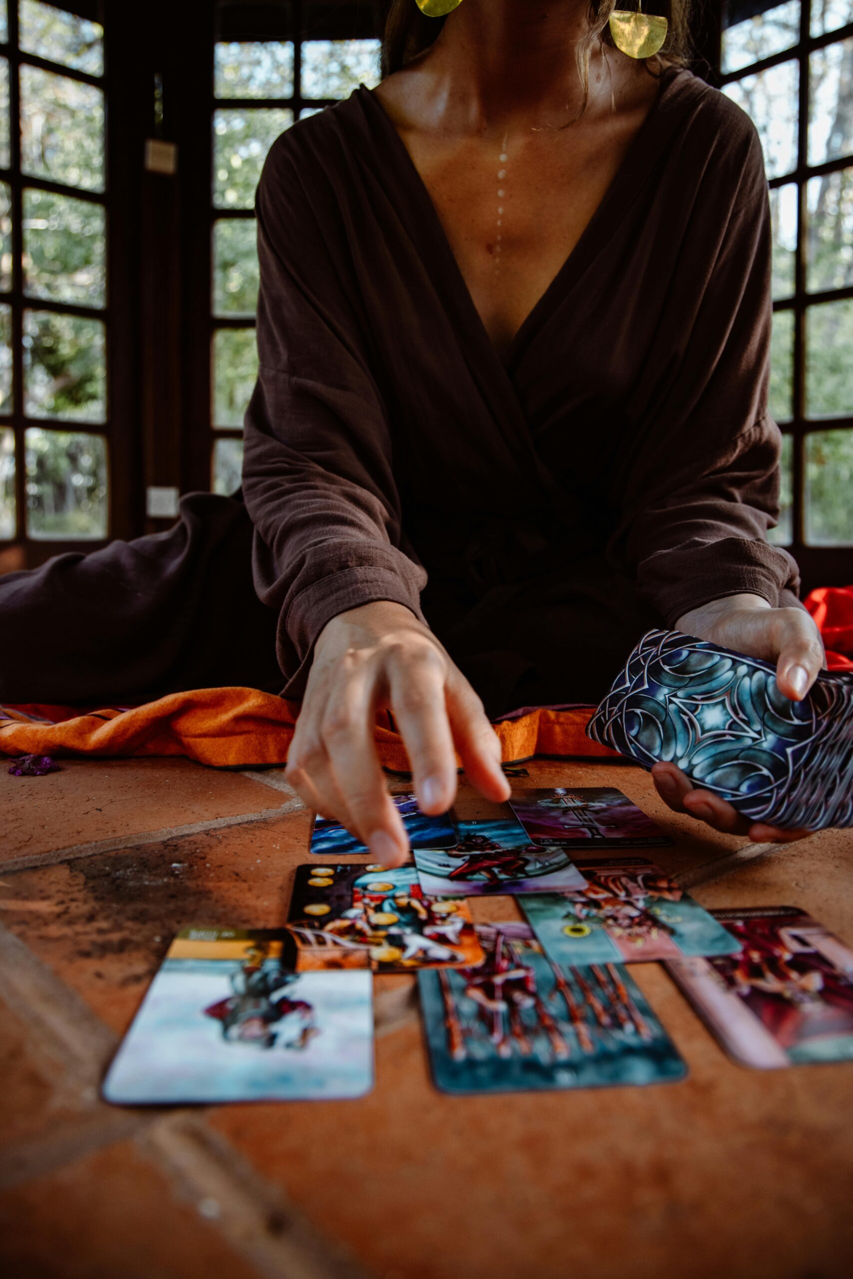 A person in a robe performs a tarot card reading on a wooden floor, creating a mystical ambiance.