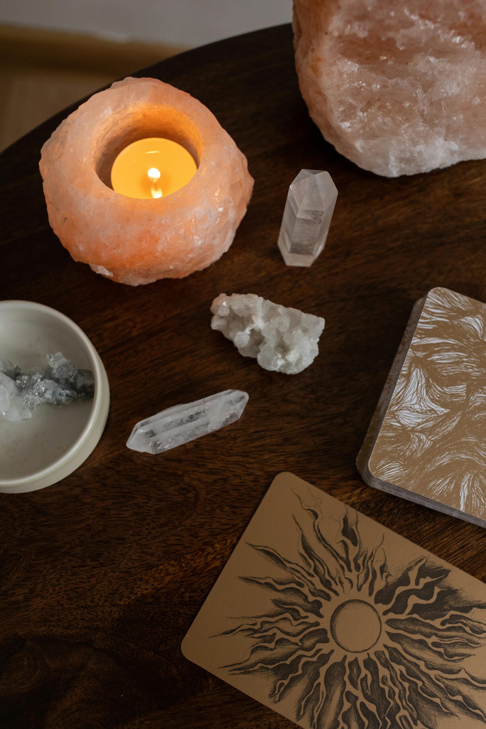 A serene top view of crystals, a candle, and esoteric cards on a wooden table.